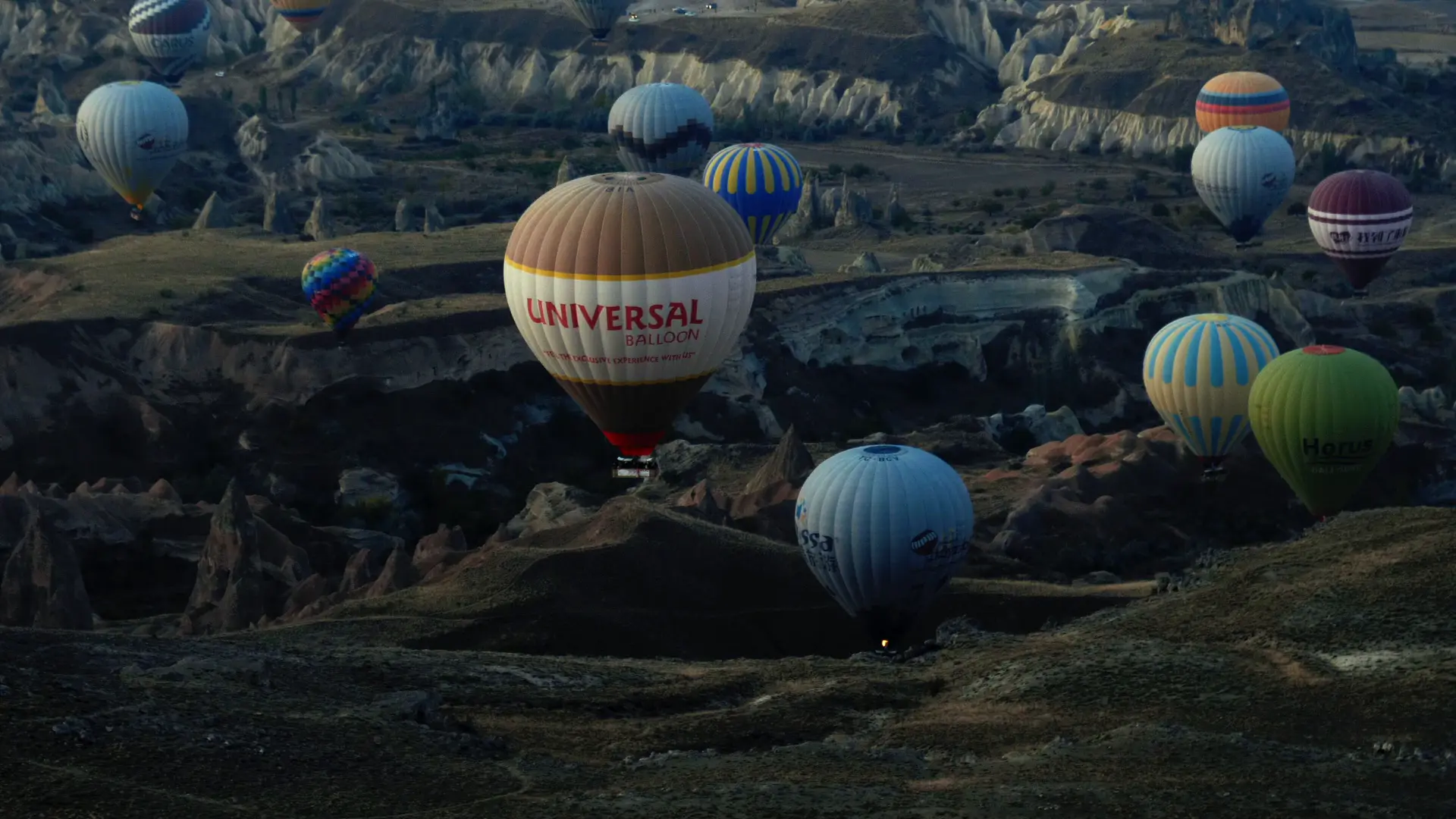 Hot air balloons floating over dramatic aerial landscape